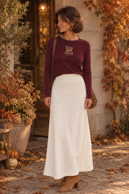 Femme en t-shirt bordeaux Yes She can et jupe midi crème, décor d'automne